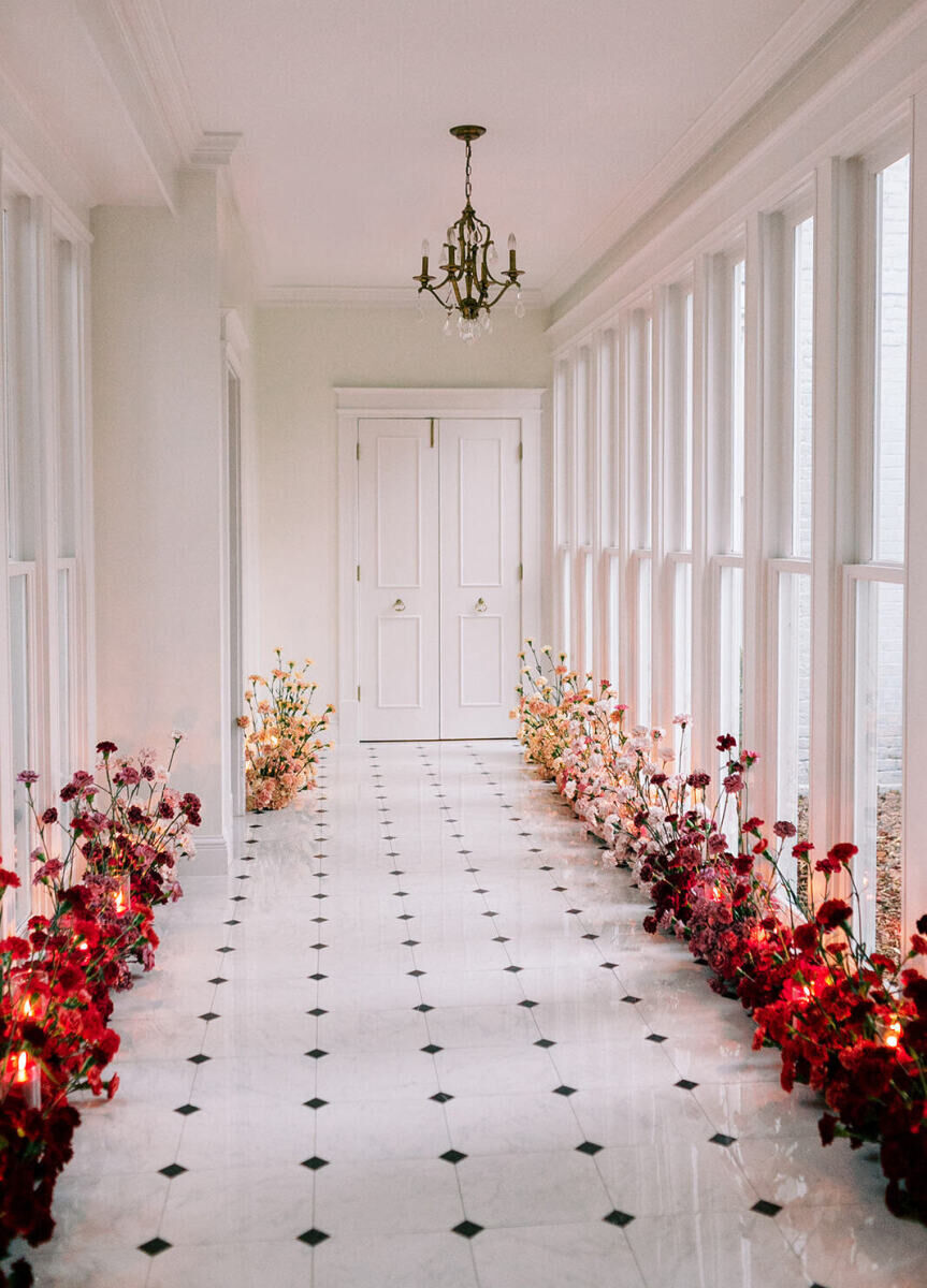 A hallway decorated with an ombre of pink flowers and candles.