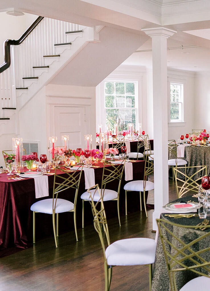 Wedding reception with red and gold tables set with multiple pieces of gold flatware for the multi-meal dinner reception.