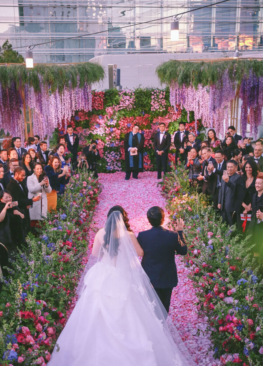 Best Places for a Colorful Wedding: A bride being walked down a colorful floral aisle at Aria.