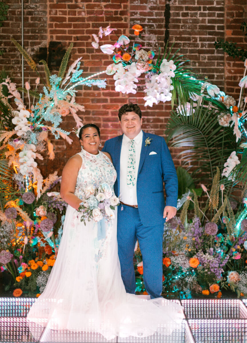 Best Places for a Colorful Wedding: A bride and groom smiling and posing on a colorful dance floor and a circular floral arch.