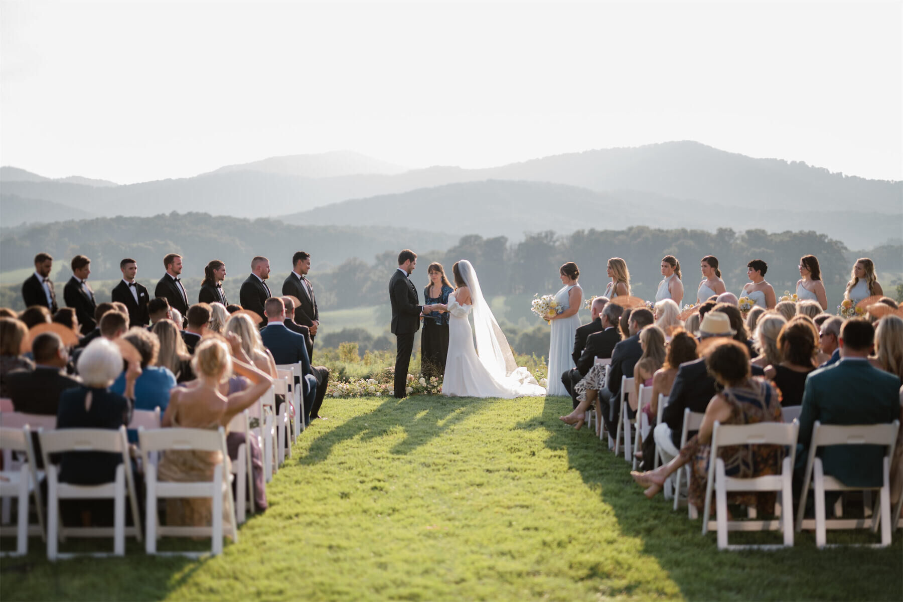 An outdoor ceremony on a lawn at Pippin Hill Farm & Vineyards with mountain views behind the bride and groom.