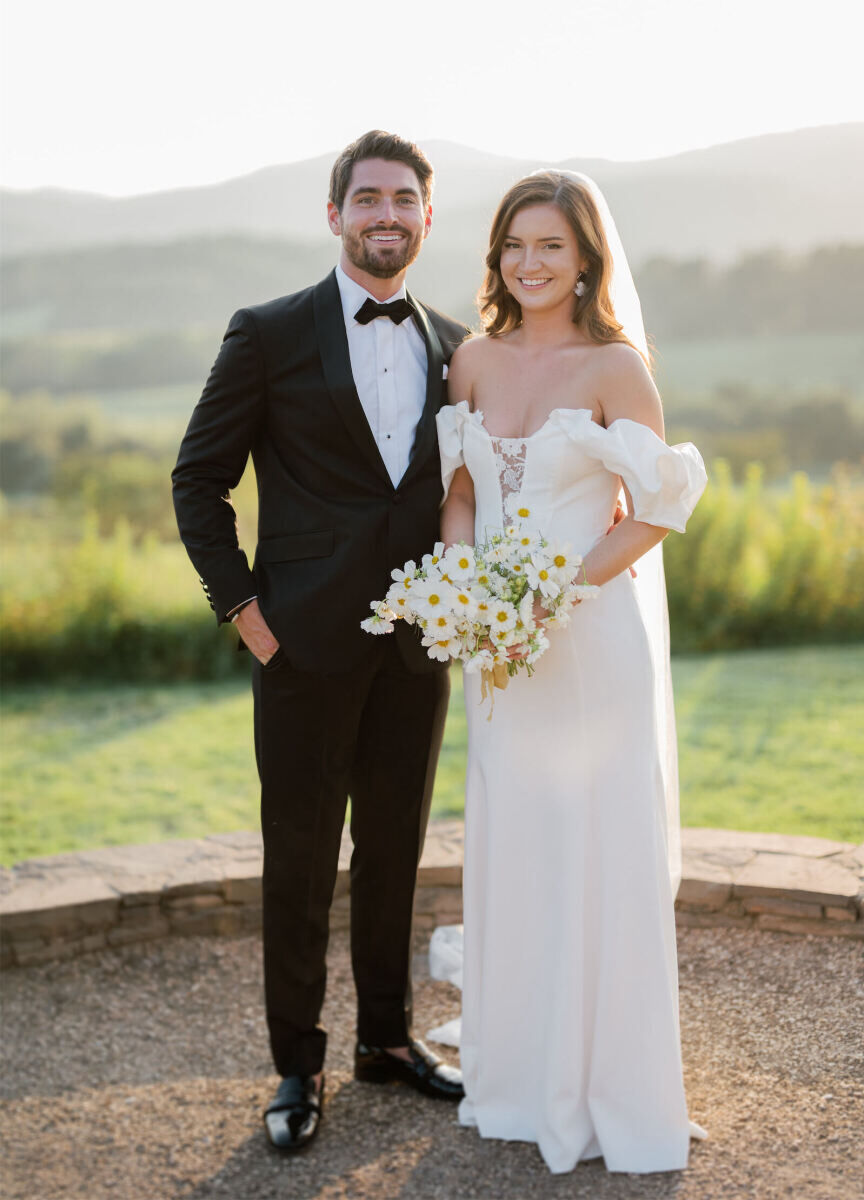 A groom and bride smile in a portrait taken at their venue—Pippin Hill Farm & Vineyards—during their cottagecore wedding, which incorporated lots of flowers but in a whimsical way.