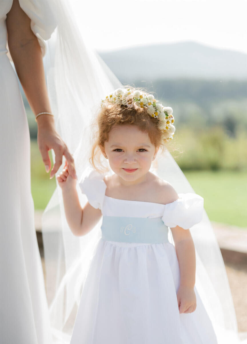 A flowergirl holds on to the bride at a cottagecore wedding.