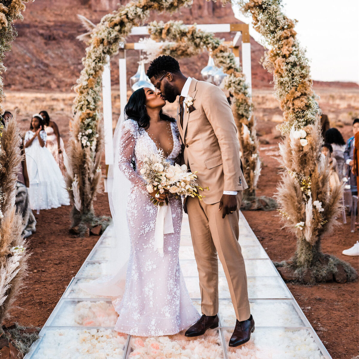 Newlyweds share a kiss at the top of their ceremony aisle during their modern desert wedding.