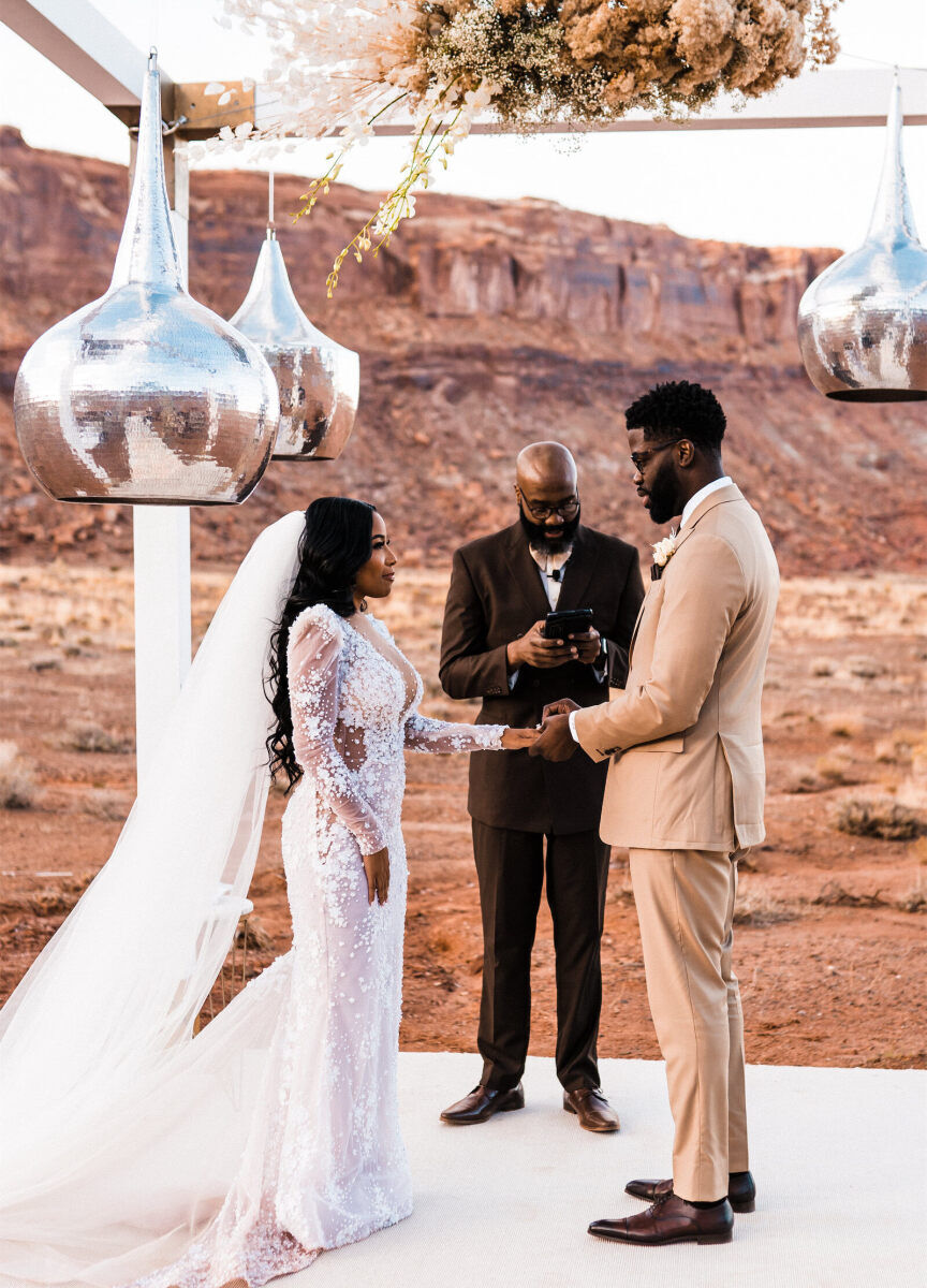 A bride and groom exchange wedding rings during the ceremony of their desert wedding.