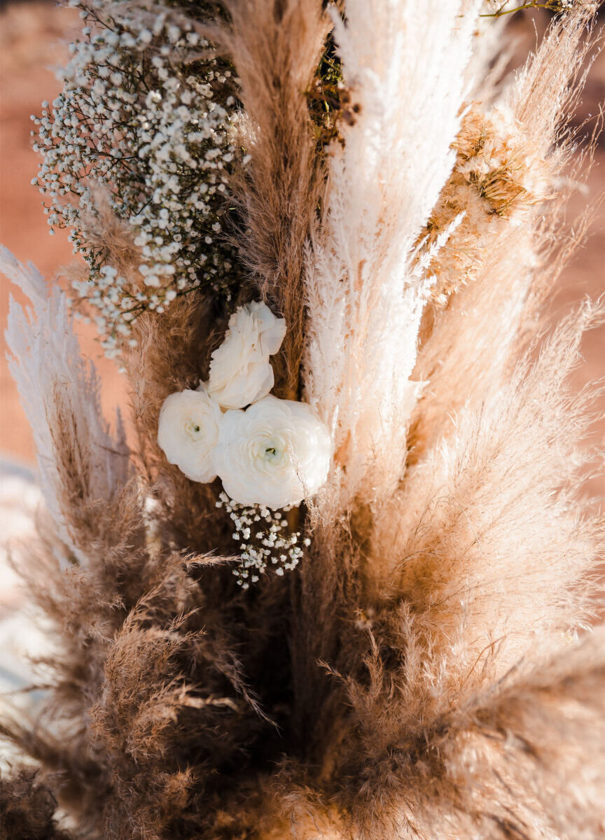 Flowers and grasses came together in the ceremony decor of a desert wedding, which had a color palette of whites and browns that matched the scenery.