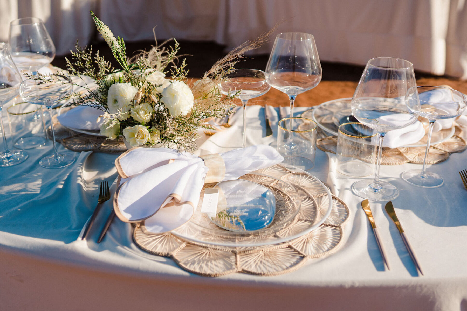 Woven chargers, clear plates, and edged napkins created a beautiful tablescape at this modern, bohemian desert wedding.