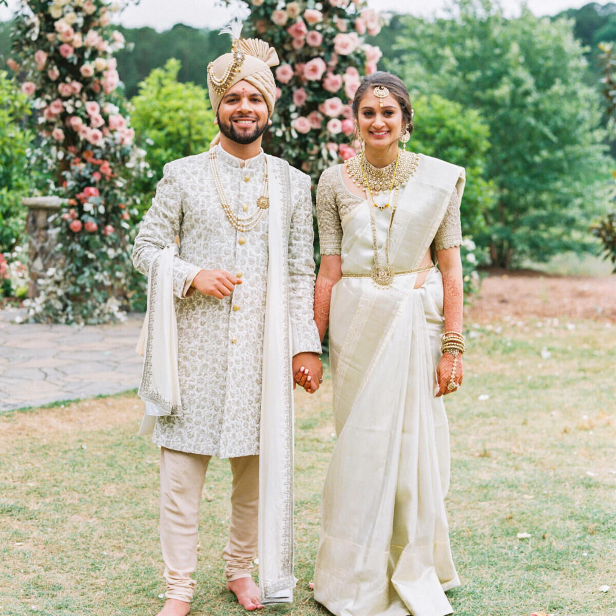 A groom and bride in front of their pink-and-white mandap at their destination Indian wedding ceremony in Raleigh, North Carolina.