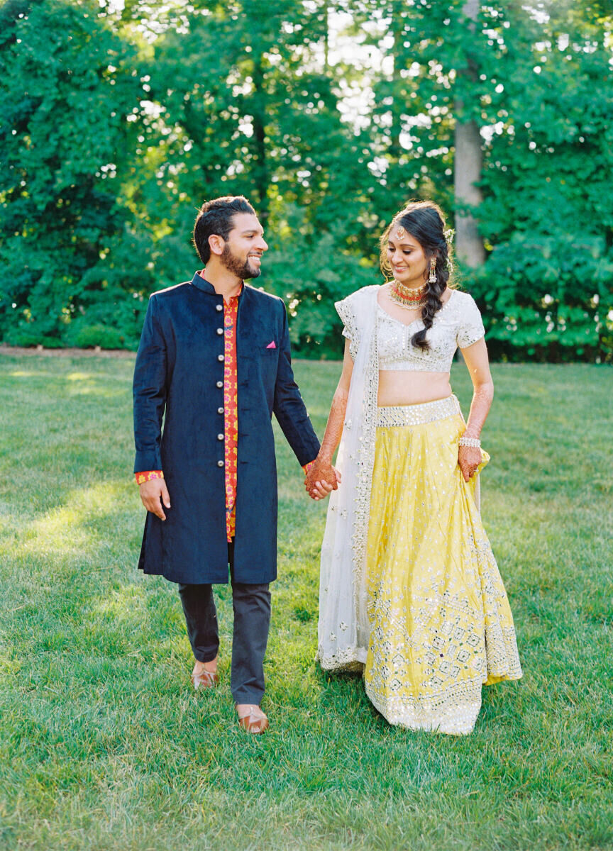A groom and bride hold hands and walk the grounds of the North Carolina hotel where much of their destination Indian wedding weekend took place.