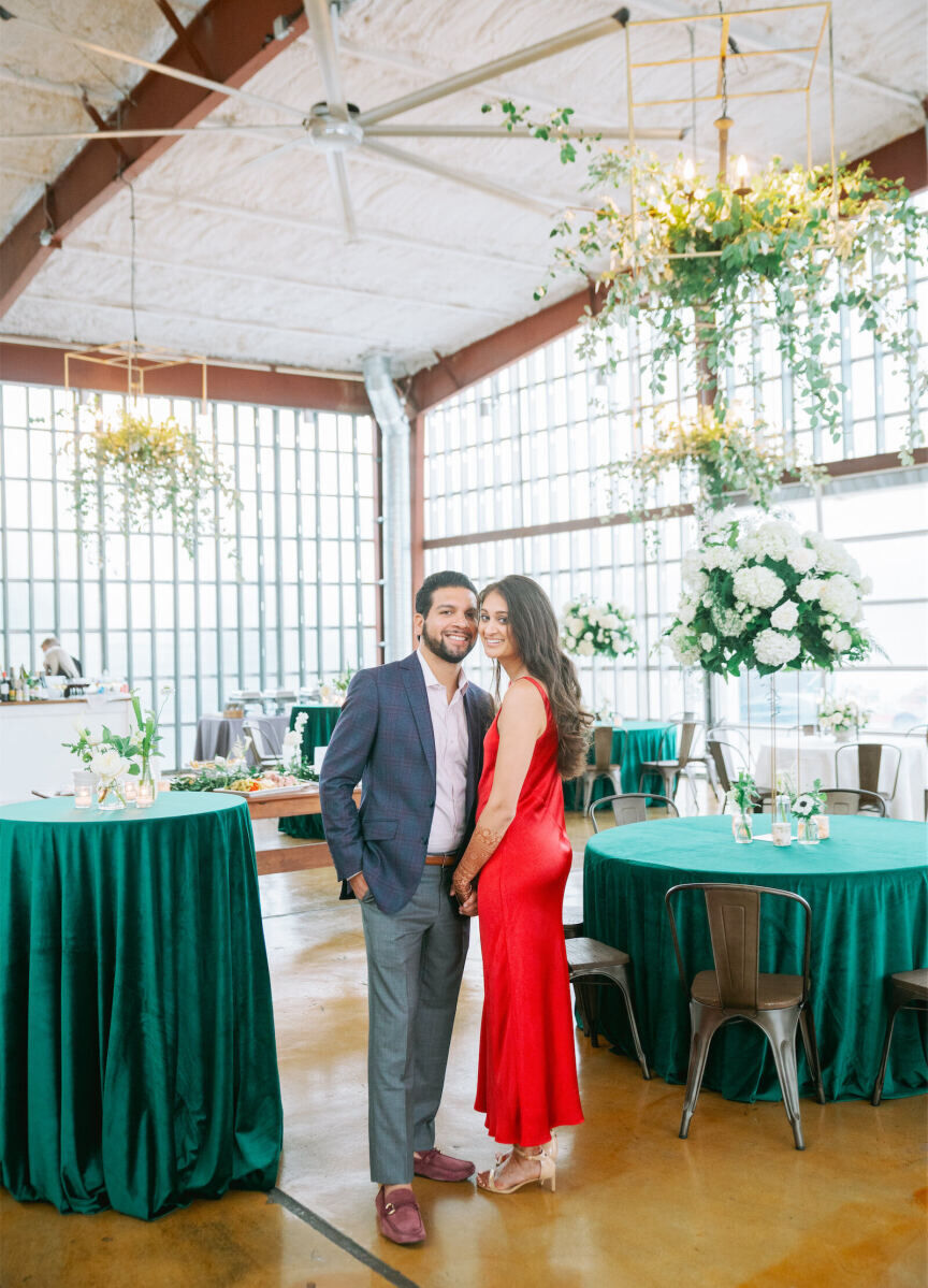 A groom and bride pose for a portrait in the industrial greenhouse where their welcome dinner took place. It was just one of the events that comprised their destination Indian wedding weekend.