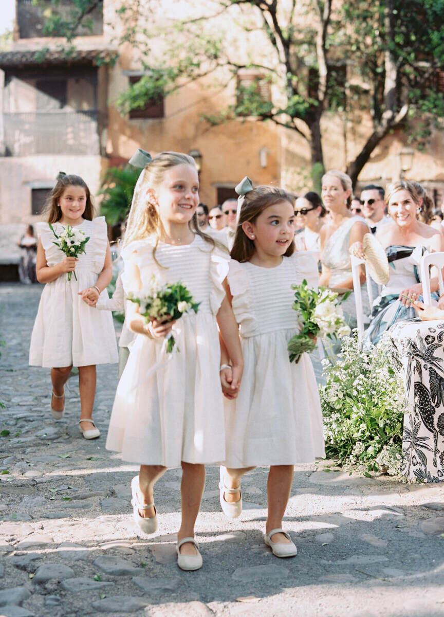 A trio of flower girls walk down the aisle during the ceremony of a destination wedding in Casa de Campo Resort & Villas.