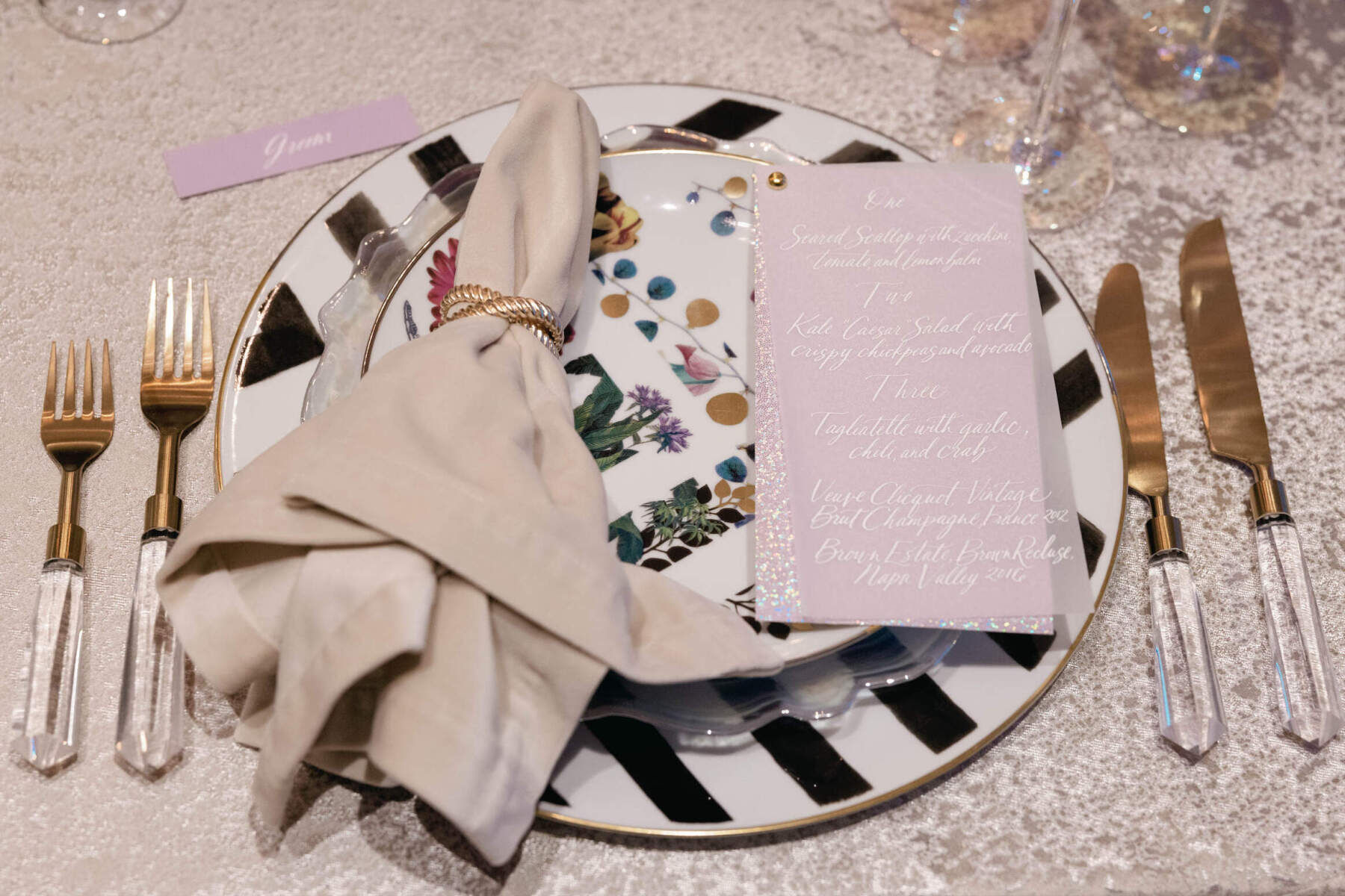 Elopement Wedding: A place-setting combining various patterned plates, clear flatware, and a menu calligraphed on vellum paper.