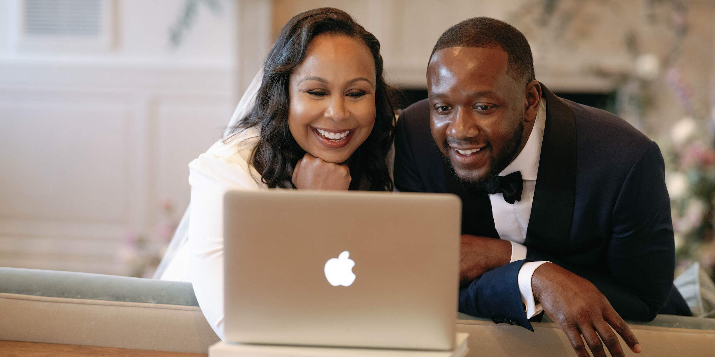 Elopement Wedding: A pandemic bride and groom sit at a laptop computer, FaceTiming their families during their intimate elopement.