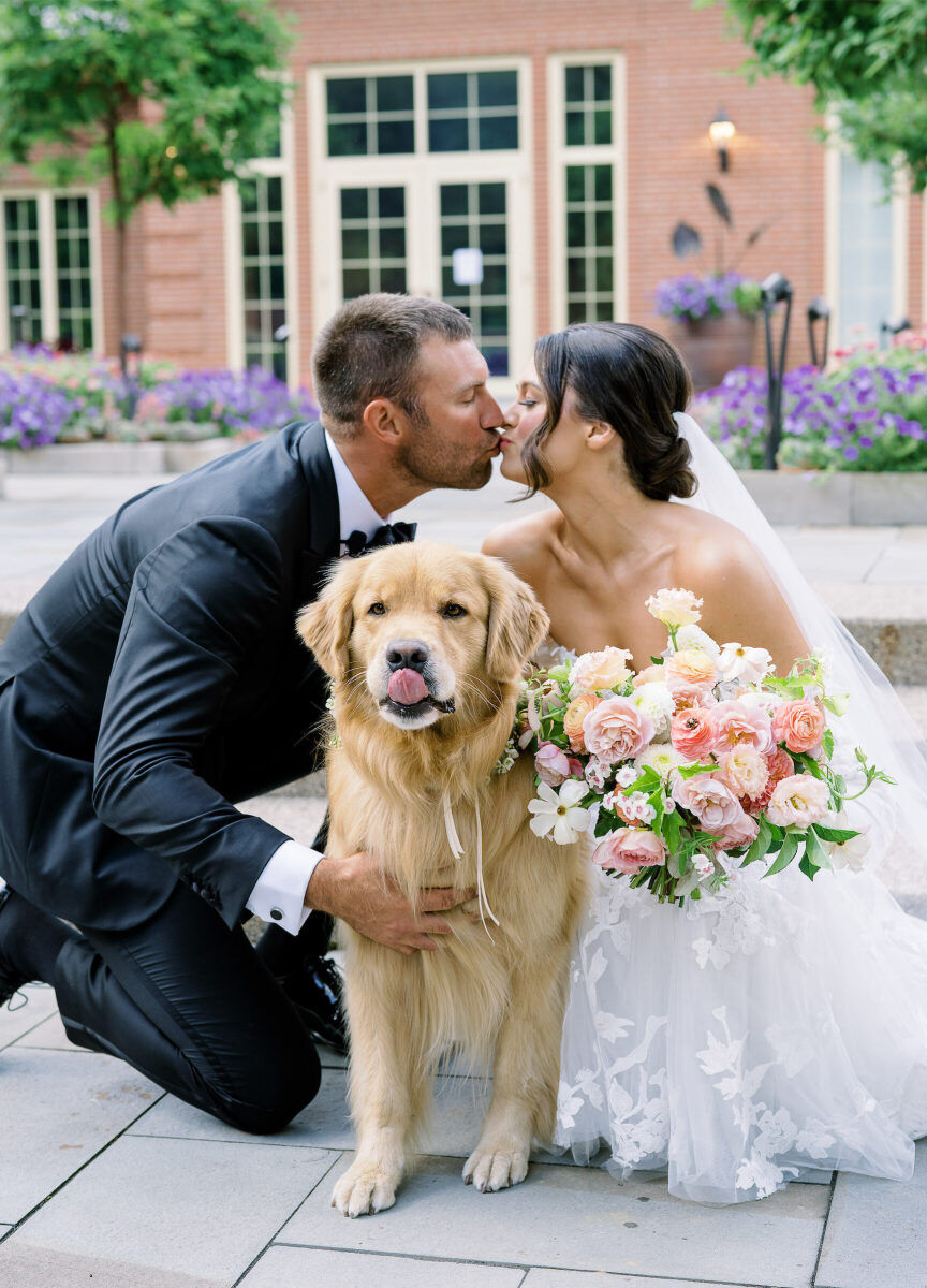 A groom and bride kiss with their dog in the foreground, at their enchanted garden wedding.