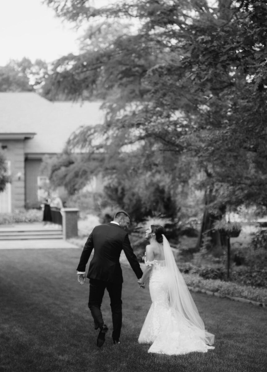 A newlywed couple walk on the grounds and share a laugh during their enchanted garden wedding.