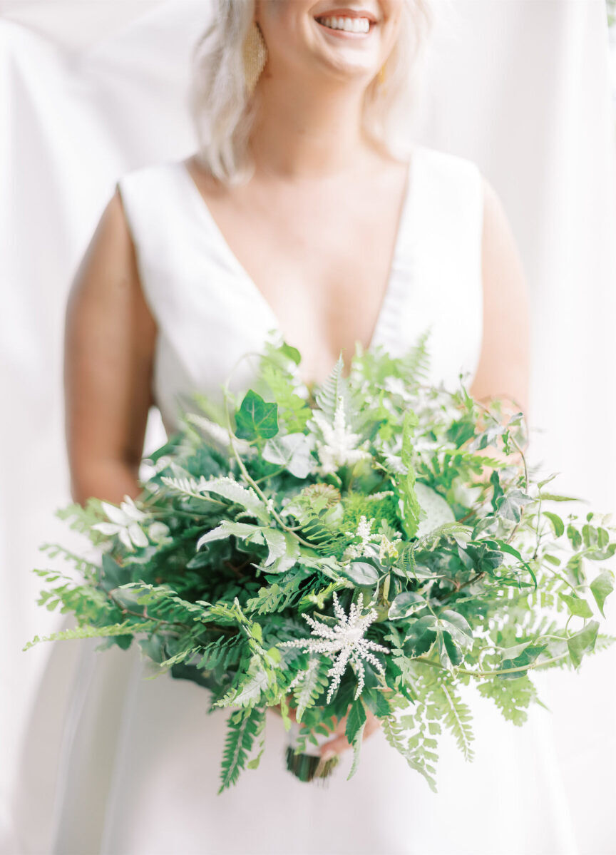 For her enchanted waterfront wedding, the bride carried a bouquet of mostly greenery with accents of white astible.