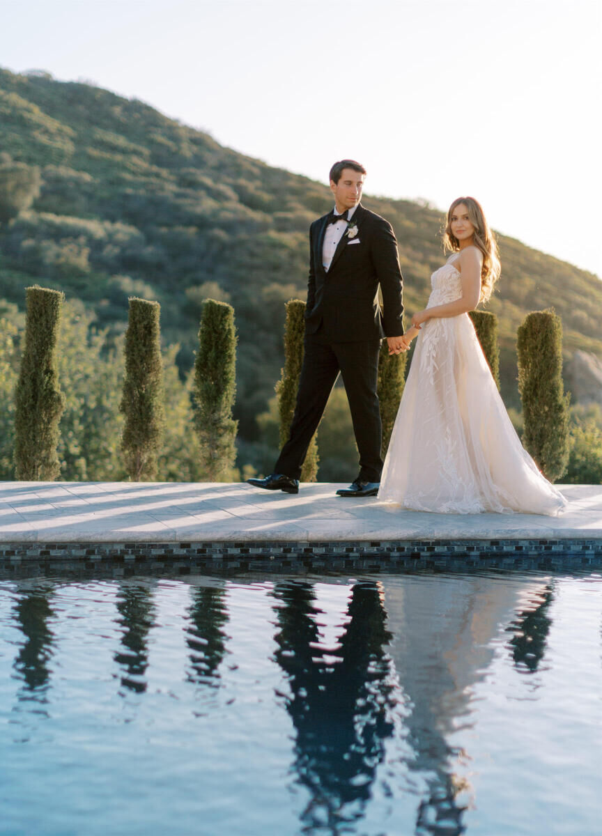 A married couple walk along a pool at their estate wedding in California.