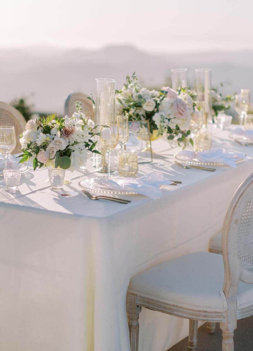 A muted reception table with white and pink floral centerpieces.