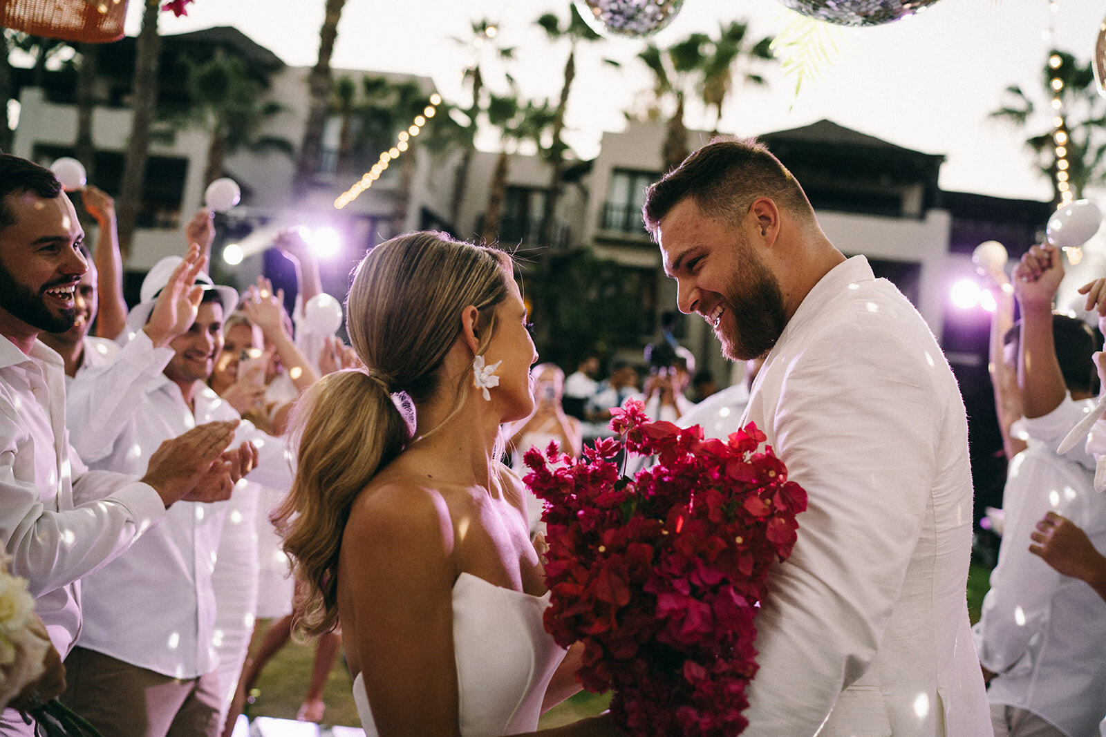 A bride and groom and their newlyweds dance at a glam beach wedding.