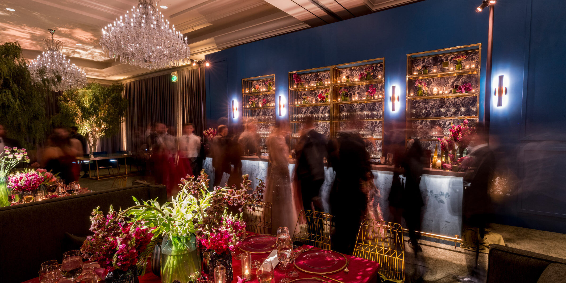 Guests converse around a custom-built bar at a glam enchanted wedding reception in the ballroom of the Four Seasons Hotel Westlake Village.
