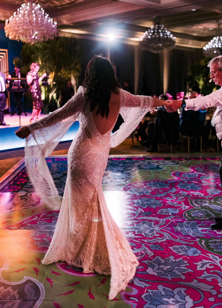 A bride and her father dance on a patterned dance floor at her glam enchanted wedding.