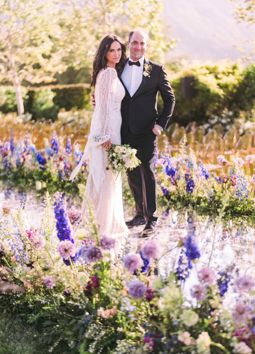 A pair of newlyweds pose on their mirrored ceremony aisle ahead of their glam enchanted wedding in California.