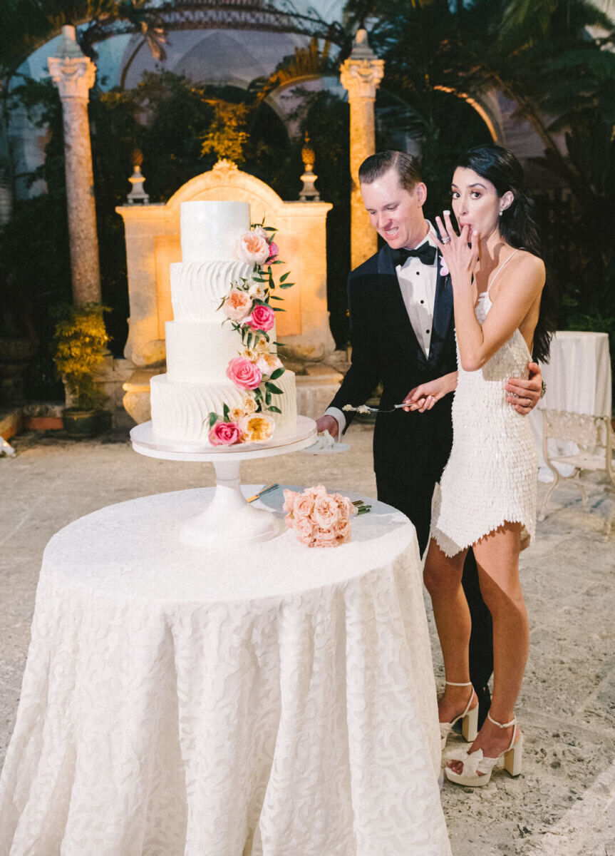 Newlyweds cut their cake during the reception of their glam, garden wedding.