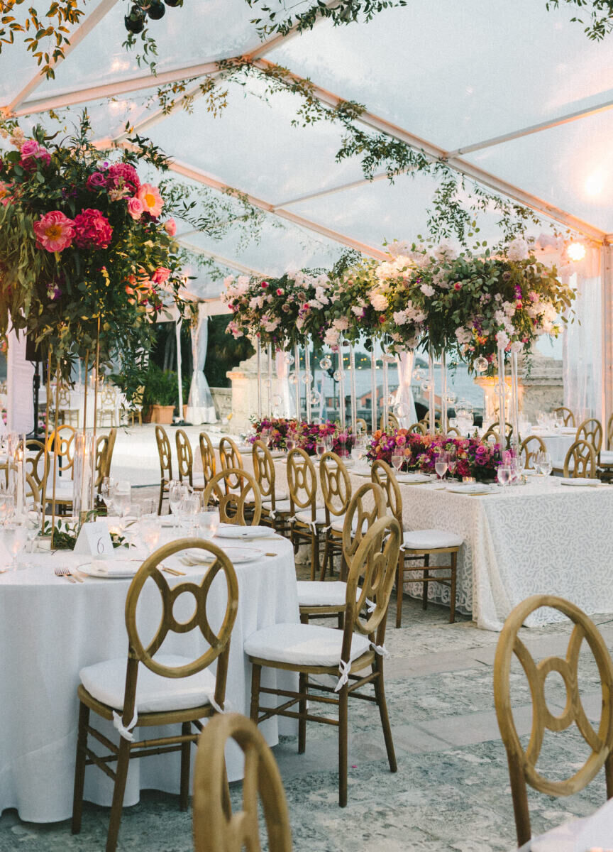 A glam, garden wedding reception in a tent, with fuchsia floral centerpieces.
