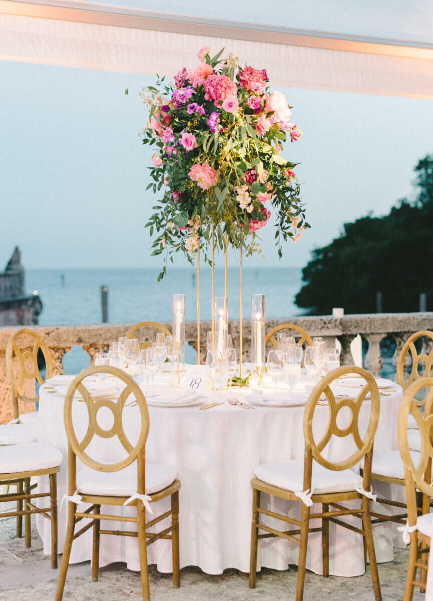 A round table set with wood chairs and a tall floral centerpiece fit the glam, garden wedding vibe.