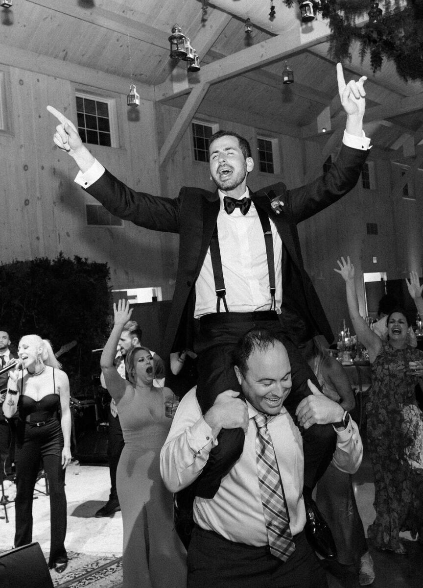 The groom on one of his guest's shoulders during the lively reception at his Glenmere Mansion wedding.