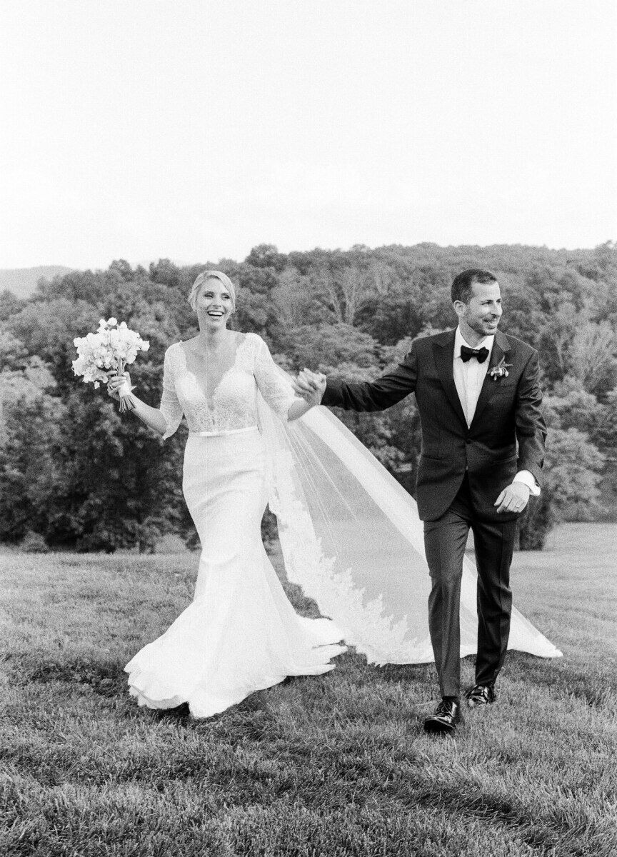 An elated bride and groom walk on the lawn hand-in-hand at their Glenmere Mansion wedding.