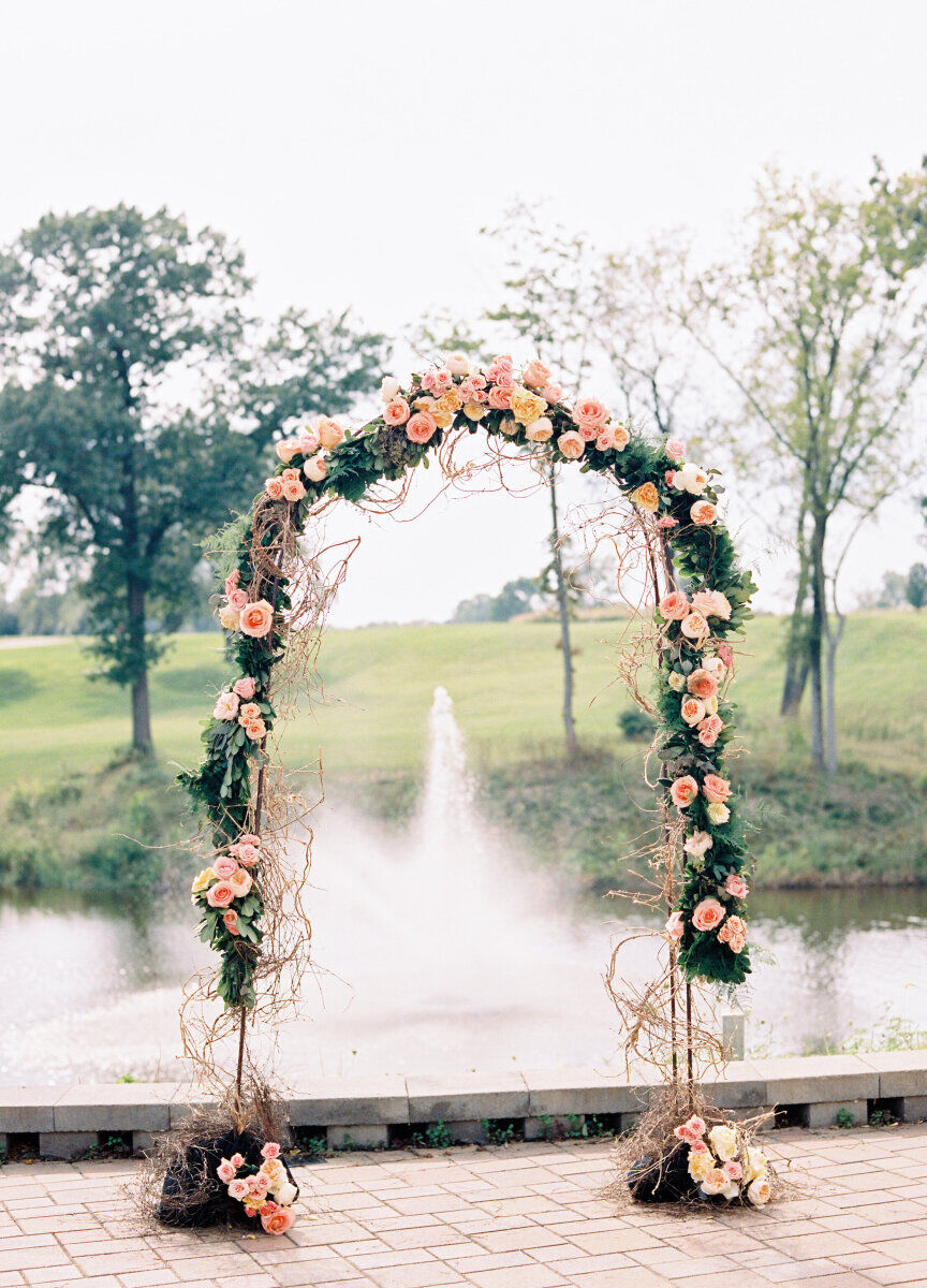 Golf Course Wedding Venues: A floral arch overlooking a pond with a fountain and golf course behind it.