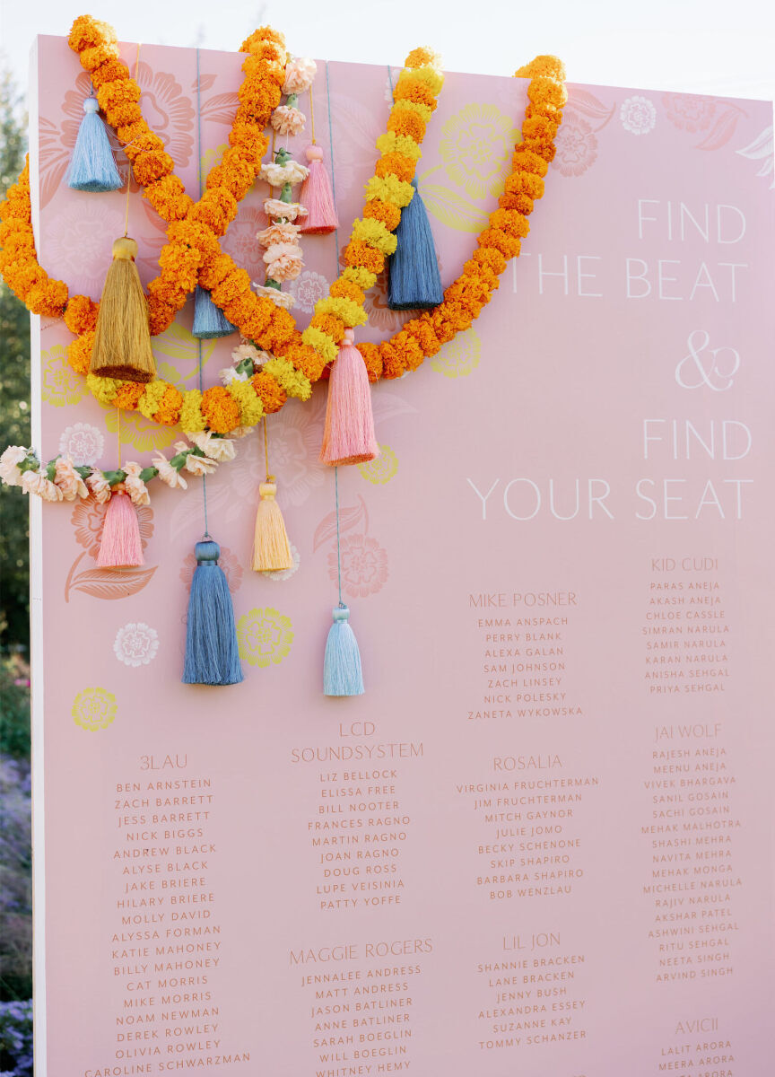 Tassels and carnation garlands hung over the corner of a music-themed seating display at an Indian fusion wedding.