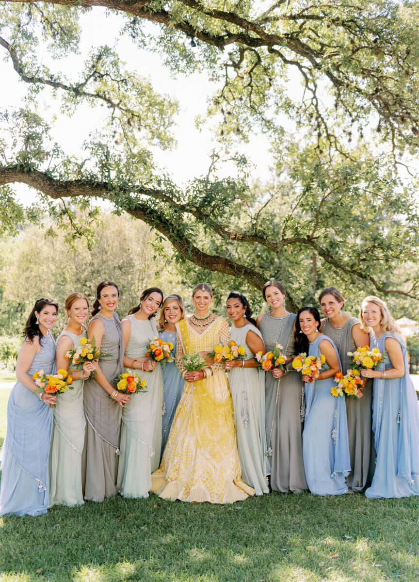 Bridesmaids in pastel blue and sage green surround a bride, wearing yellow, at an Indian fusion wedding in Austin.