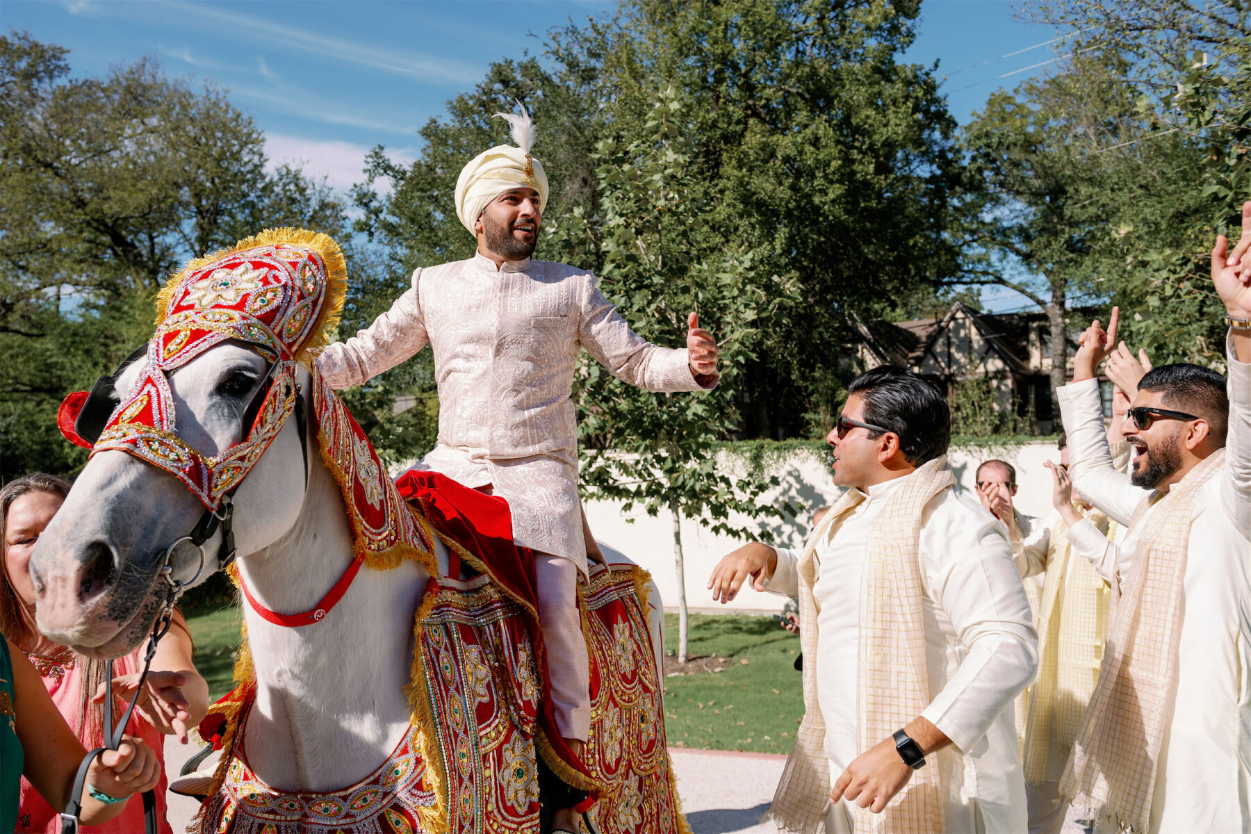 A groom on horseback enjoys his baraat on the way to his Indian fusion wedding ceremony.