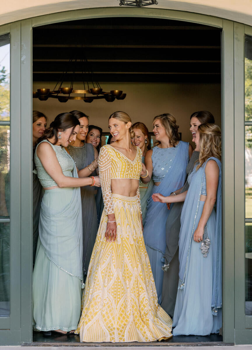 At her Indian fusion wedding, a bride wore a yellow lehenga while her bridesmaids wore soft blues and greens.