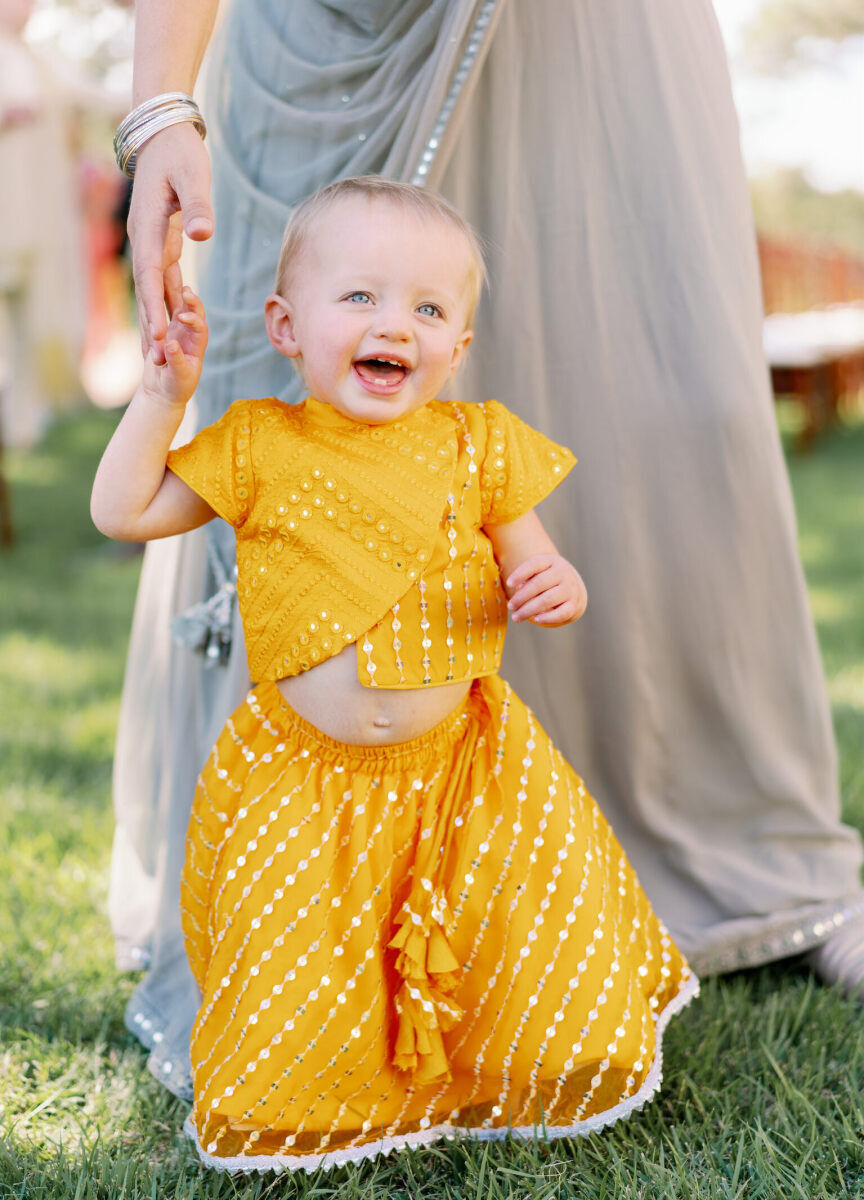 A young guest wears golden yellow and a big smile at an Indian fusion wedding.