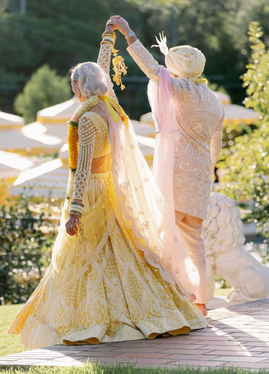 A bride and groom raise their hands in excitement post ceremony at their Indian fusion wedding in Austin.