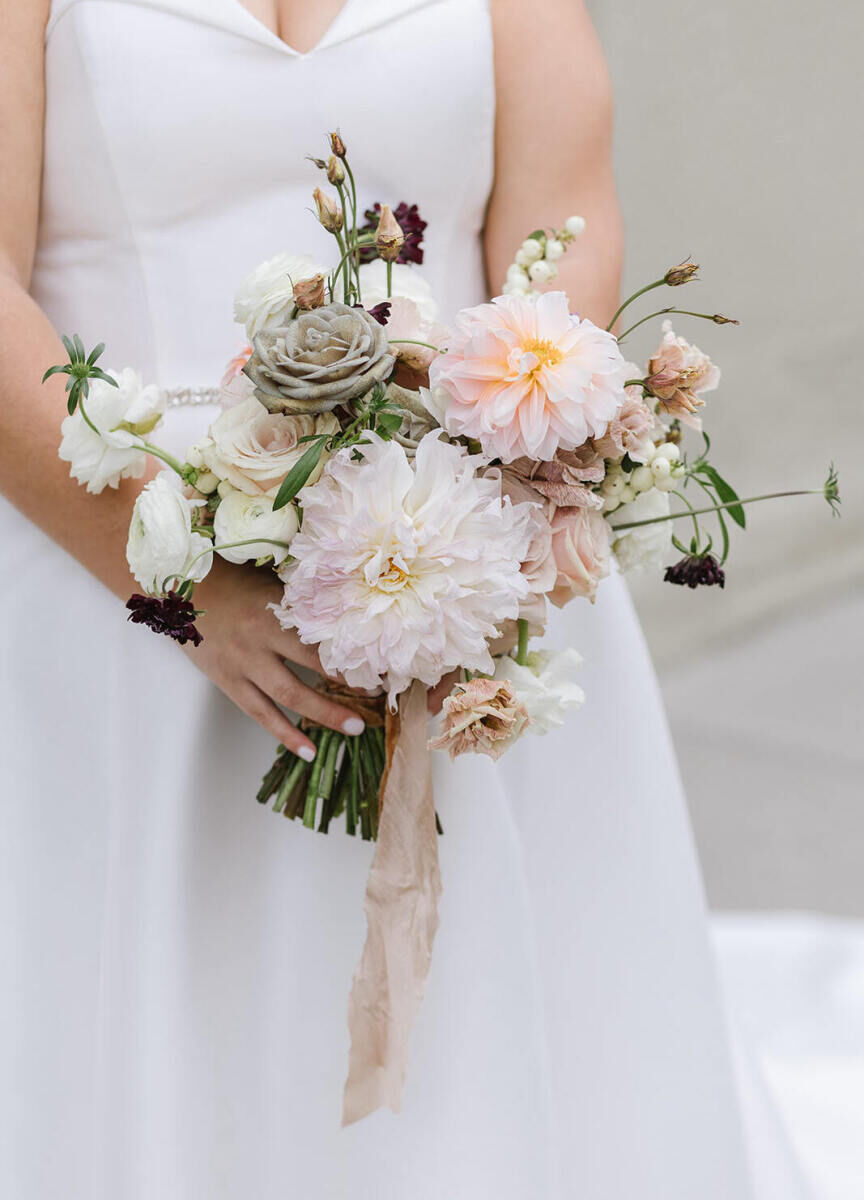 While the overall palette for the industrial wedding was more moody and dark, the bride's bouquet was softer and featured flowers in muted pastels, tied together with a raw silk ribbon in a soft taupe.