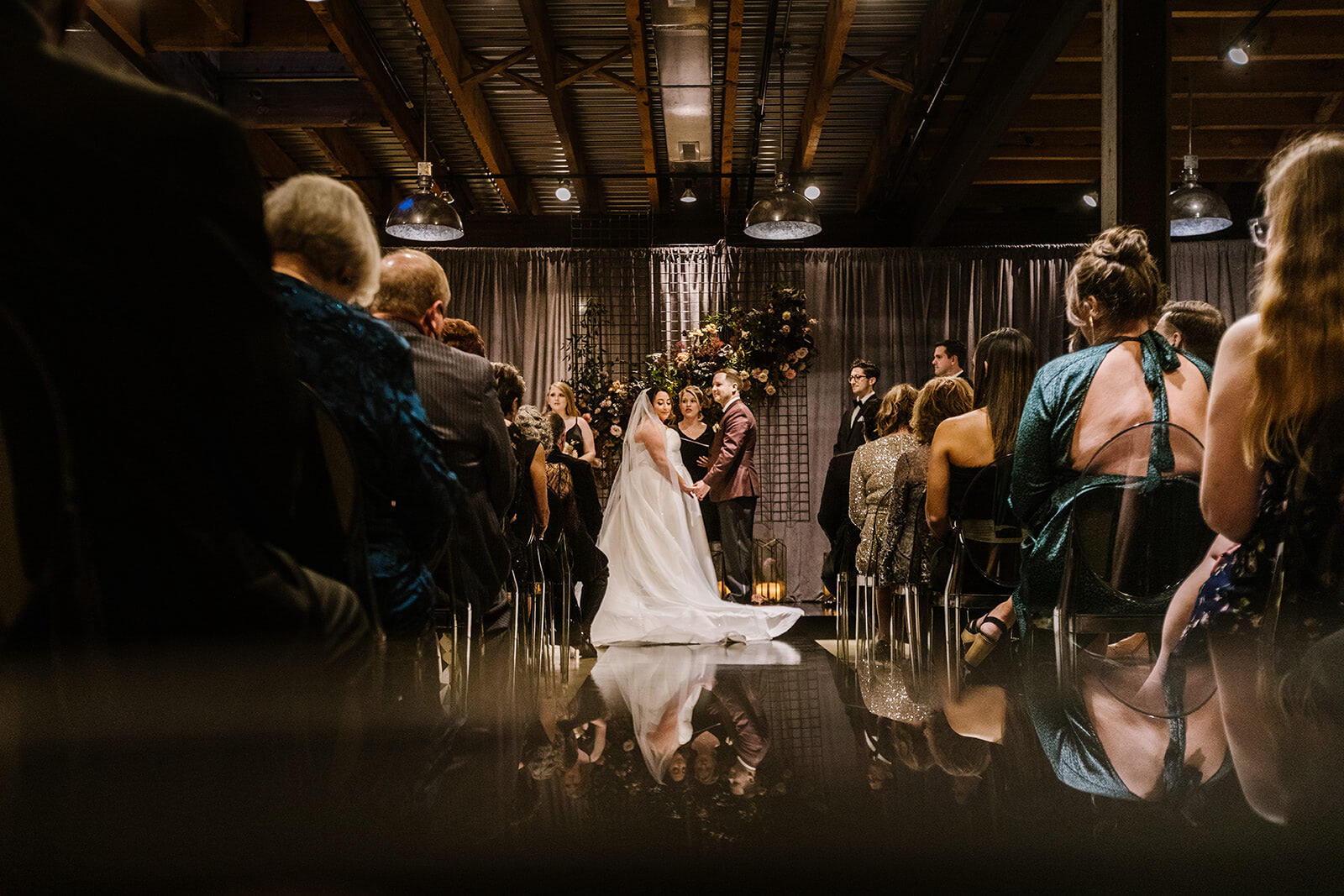 An indoor ceremony for an industrial wedding, with panels of gray drapery softening the space where the couple became husband and wife.
