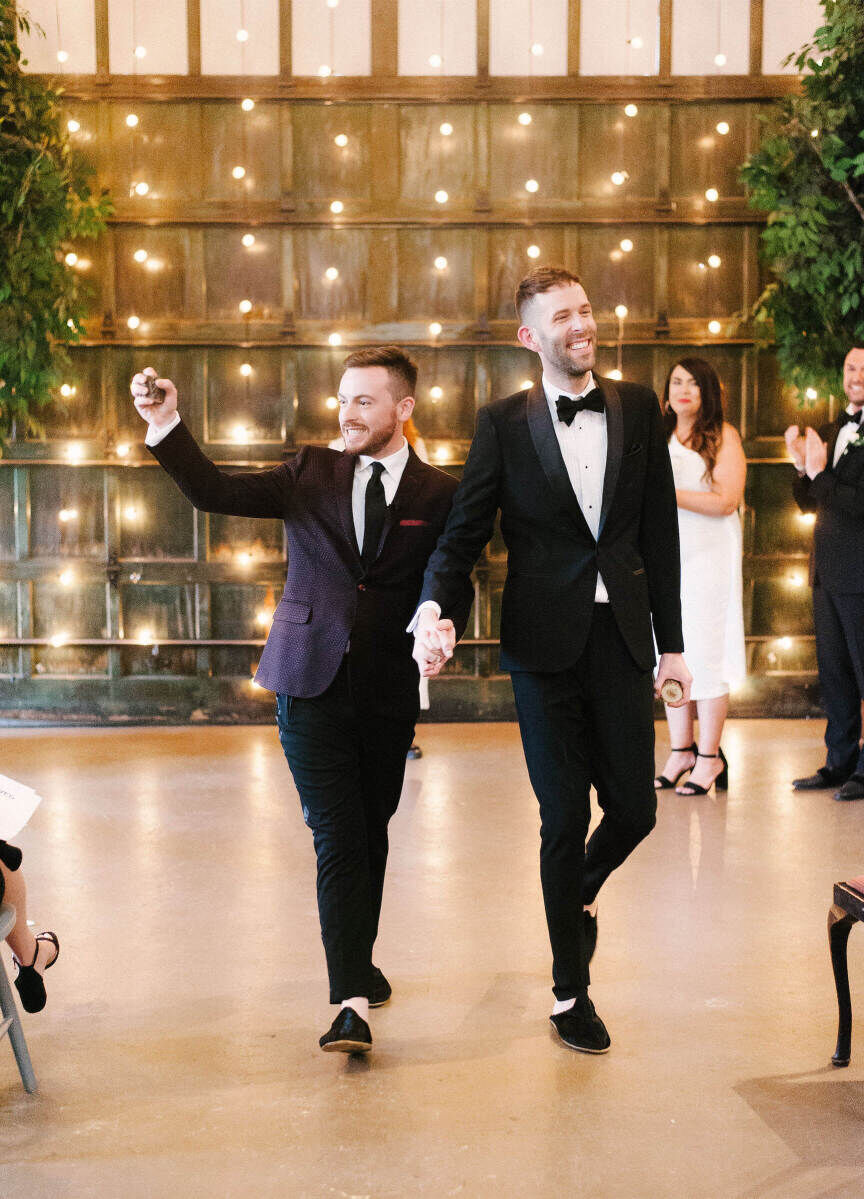 Industrial Wedding Venues: Two grooms smiling and holding hands as they walk back down the aisle together at Soho South.