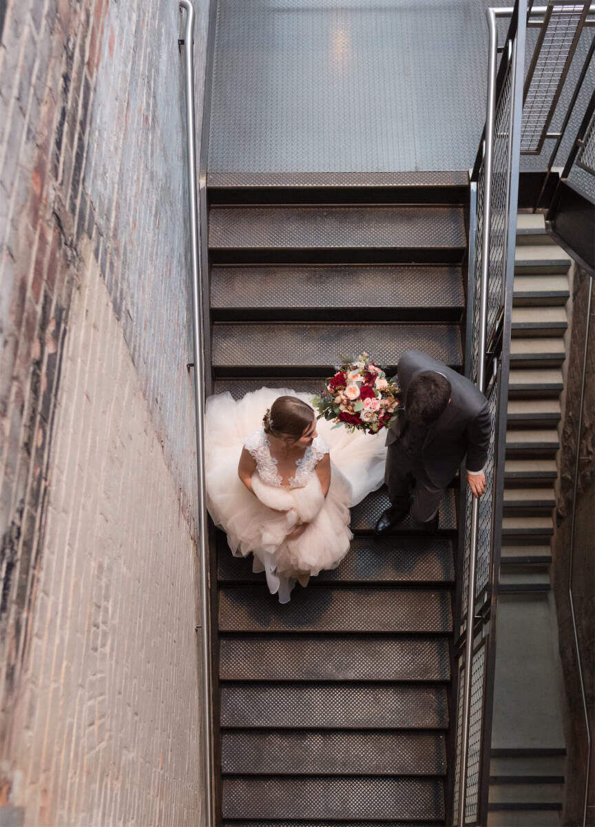 Industrial Wedding Venues: A birds-eye view of newlyweds going down a stairwell together at MASS MoCA.