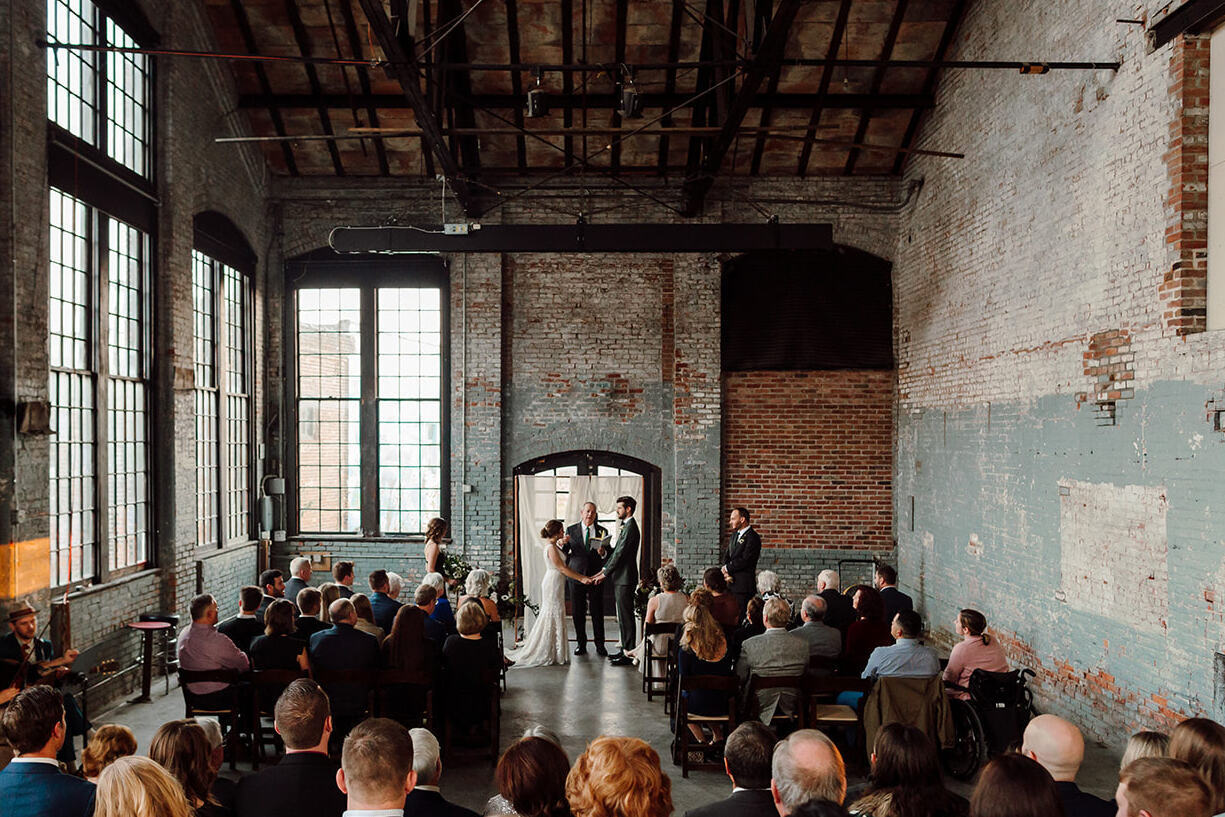 Industrial Wedding Venues: A couple standing and getting married while guests watch at Basilica Hudson.