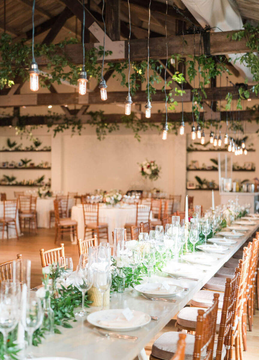 Industrial Wedding Venues: A reception setup inside Cannon Green, with wooden chairs, white tablecloths, and Edison bulbs hanging from the ceiling.