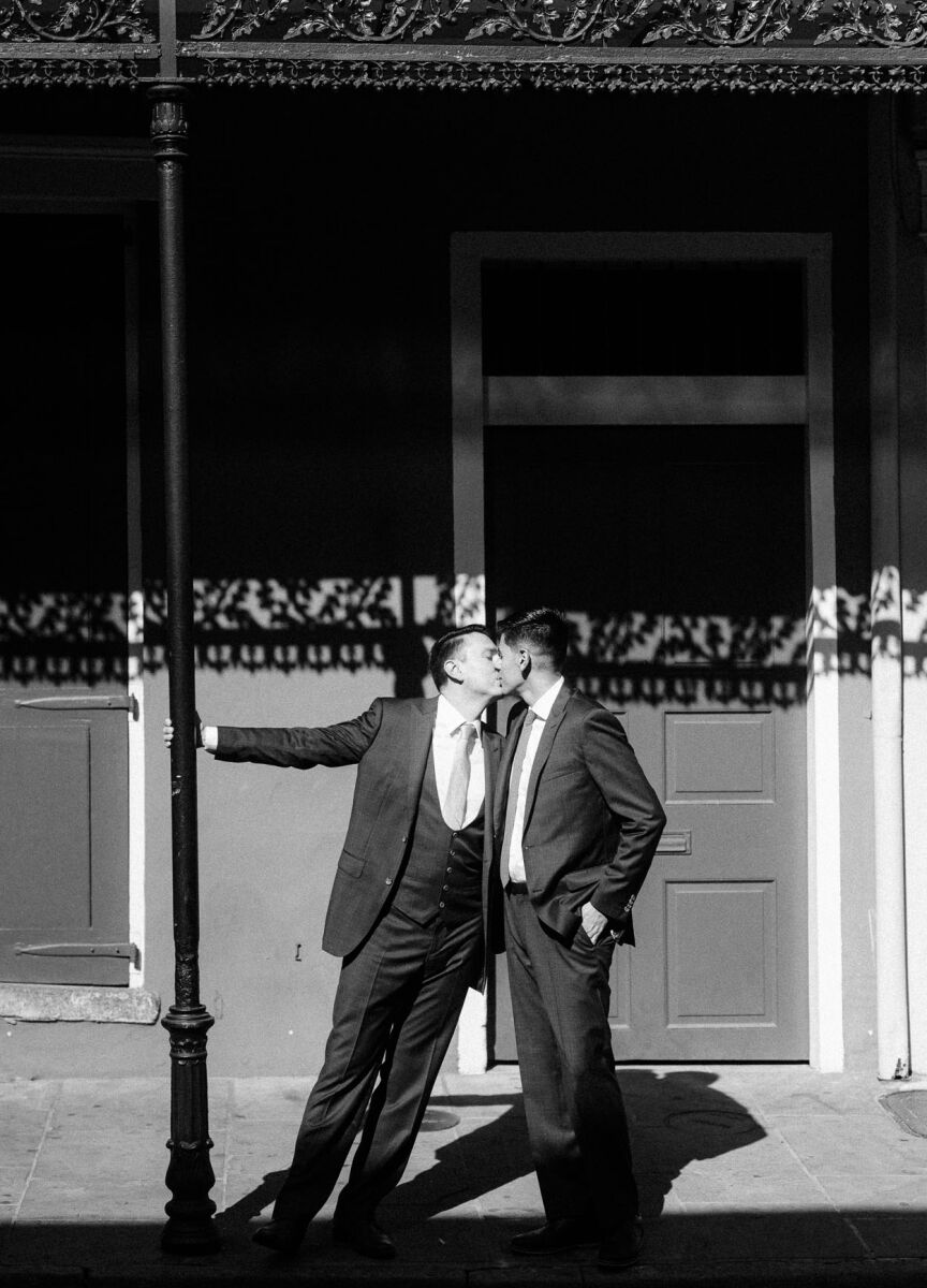 LGBTQ Wedding Ideas: A couple sharing a kiss during an outdoor photoshoot on their wedding day.