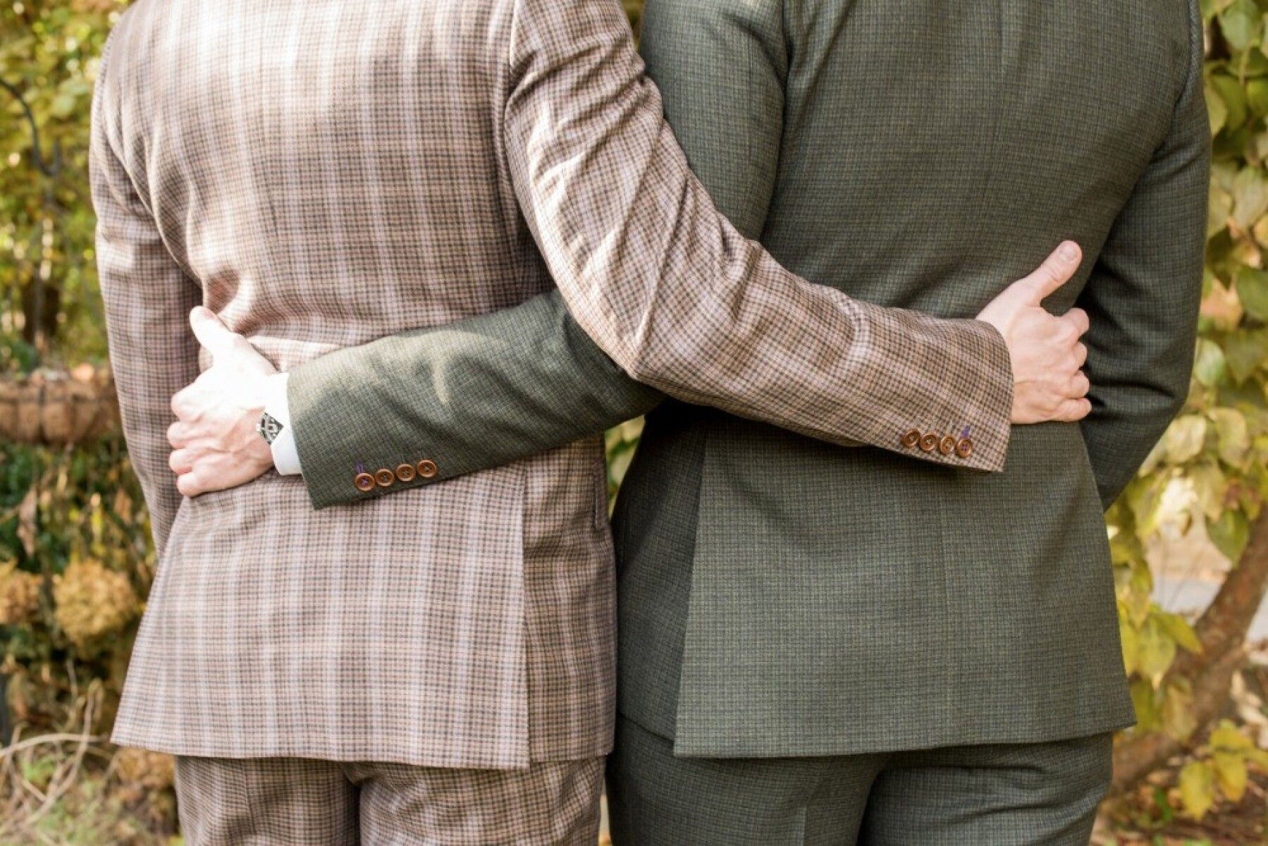 LGBTQ Wedding Ideas: Two grooms embracing with their backs facing the camera on their wedding day.