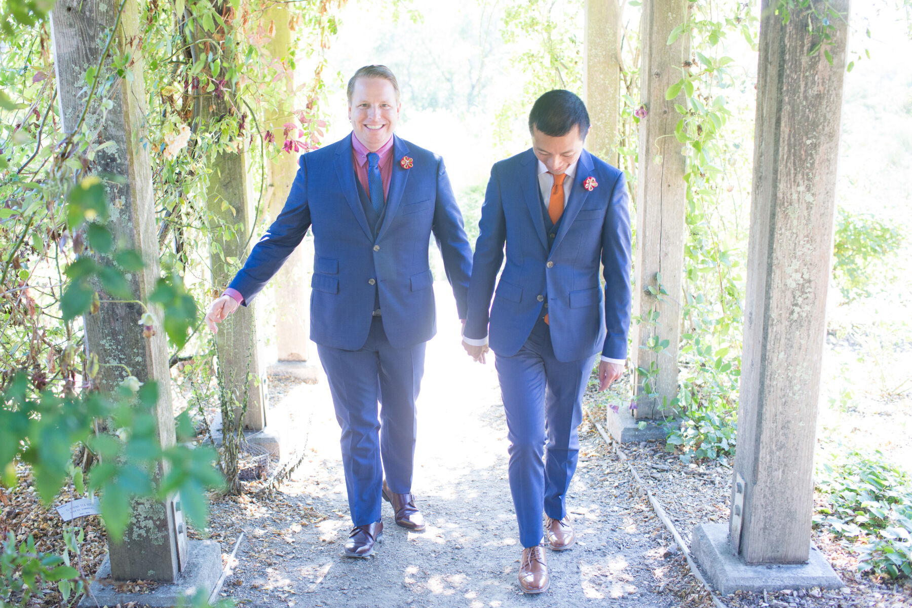 LGBTQ Wedding Ideas: Two grooms holding hands outdoors on their wedding day.