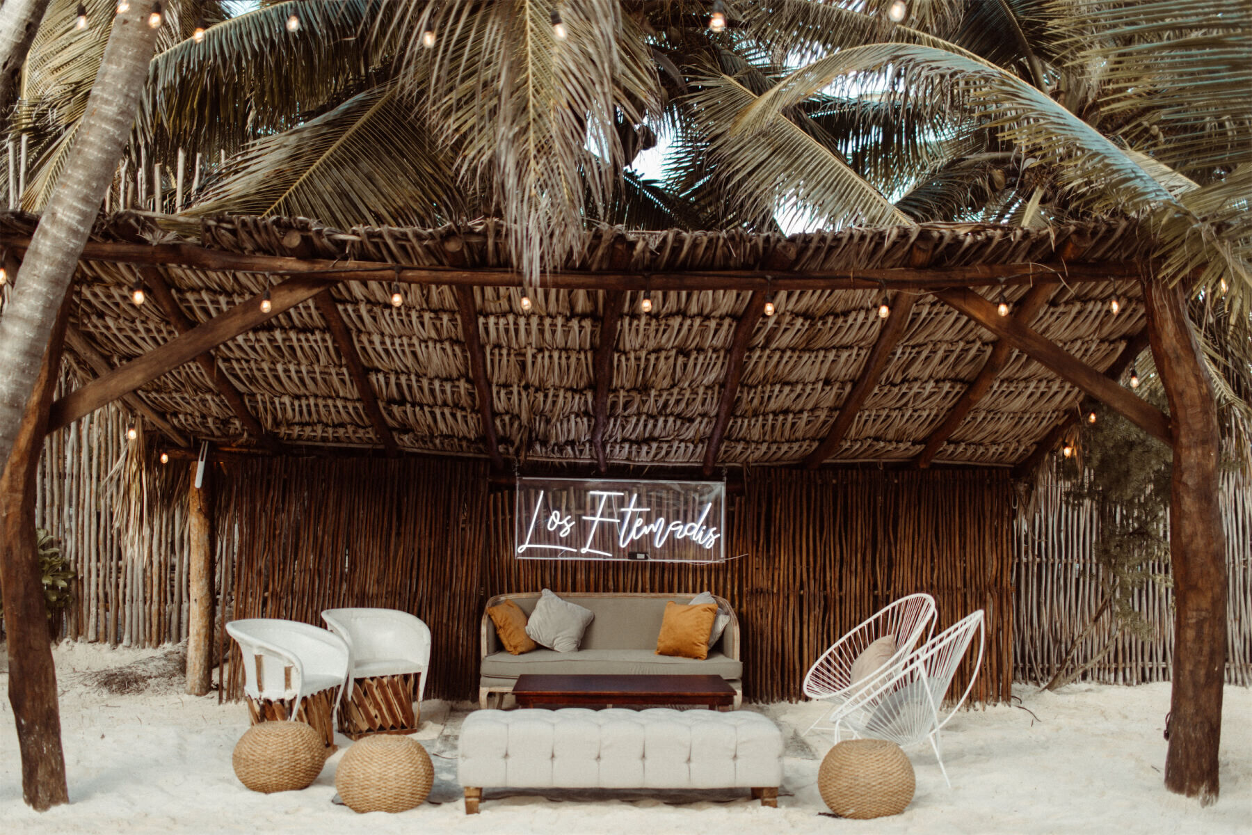 Mexican wedding: neutral modern lounge furniture underneath a straw cabana, featuring a neon sign
