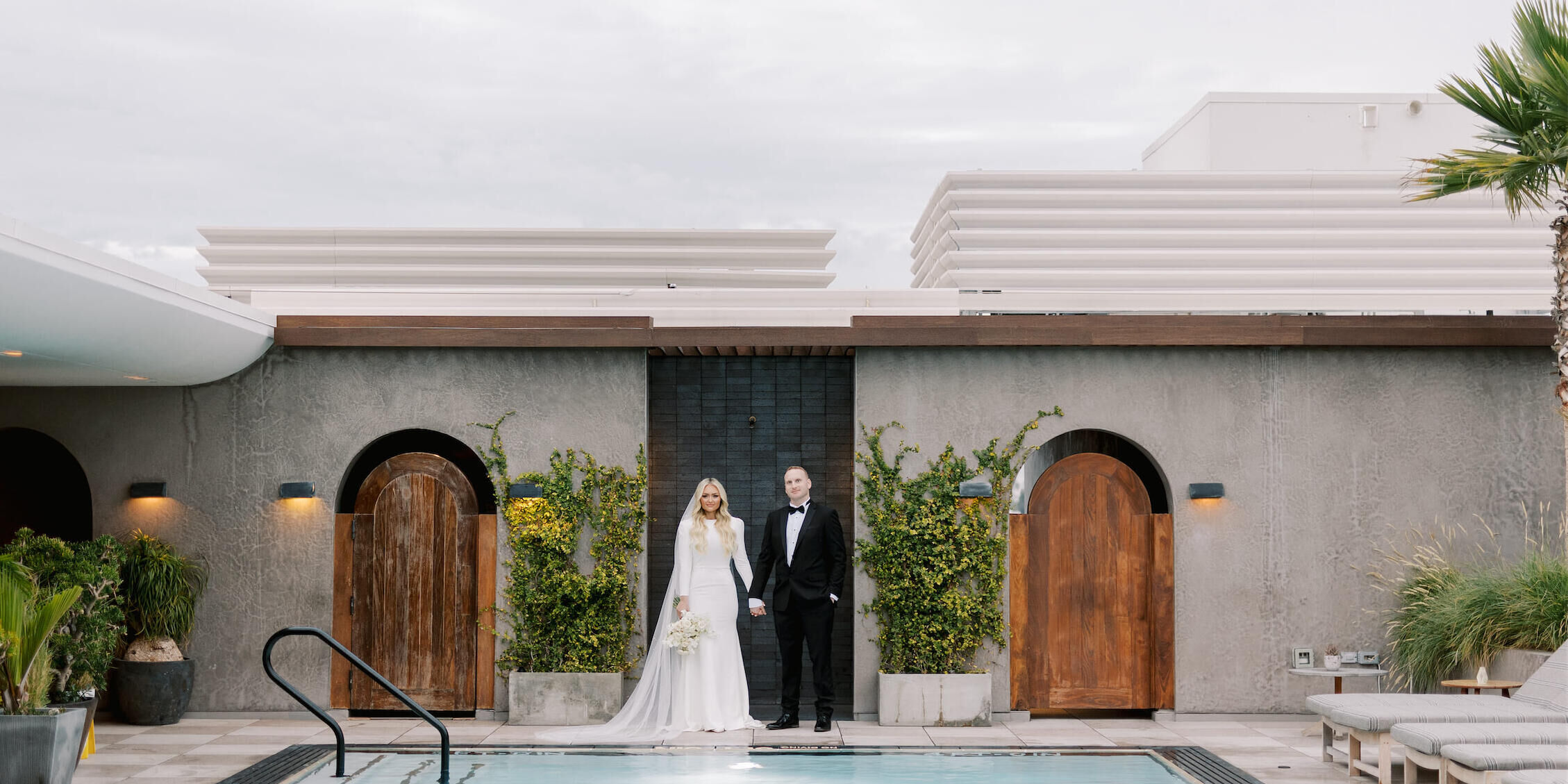 A bride and groom take a portrait by the pool of the Santa Monica Proper during their modern California wedding.