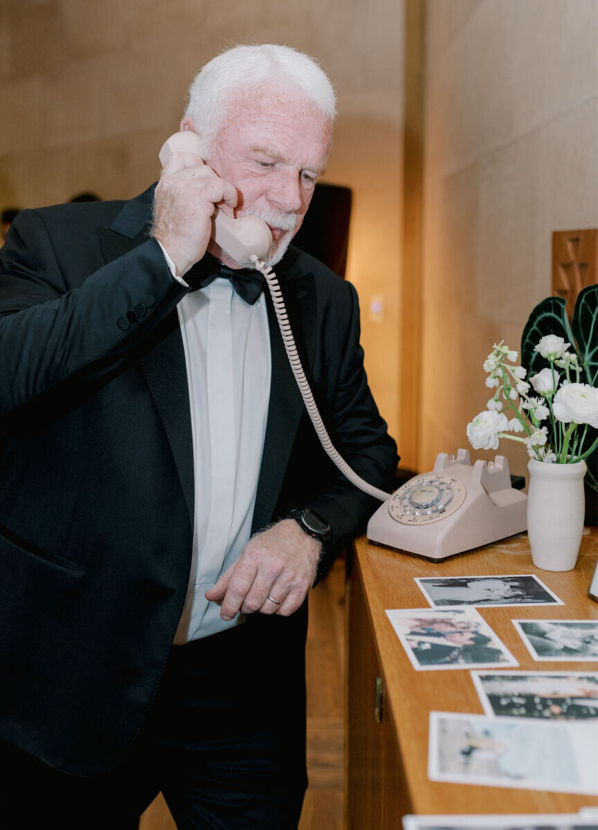 A guest leaves an audio message on a modified rotary phone for the bride and groom during their modern California wedding.